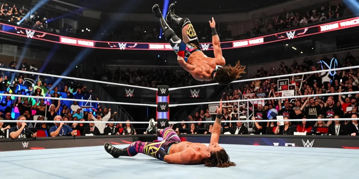 WWE superstar executing a spectacular aerial move in front of an excited crowd during a live wrestling event.